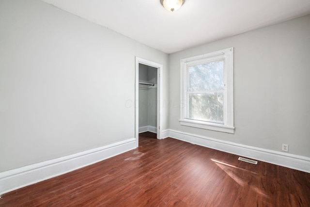 unfurnished bedroom with a closet, visible vents, baseboards, and wood finished floors