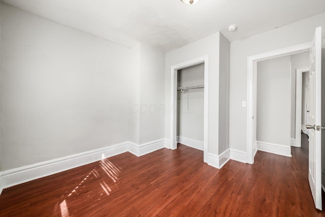 unfurnished bedroom with a closet, baseboards, and wood finished floors