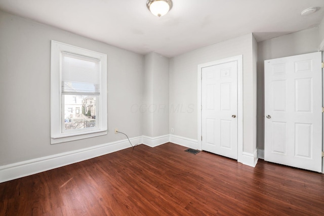 unfurnished room with dark wood-type flooring, baseboards, and visible vents