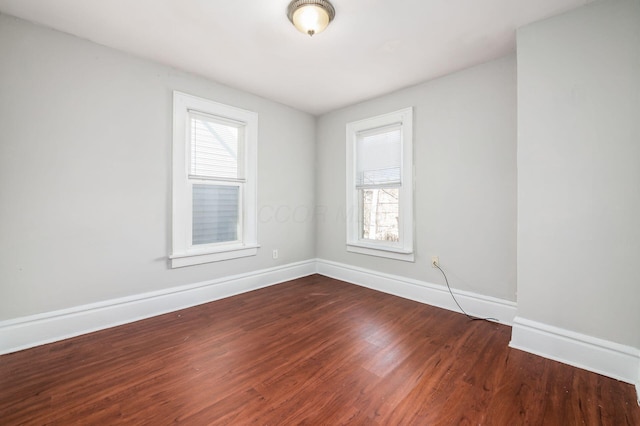 empty room featuring dark wood-type flooring and baseboards