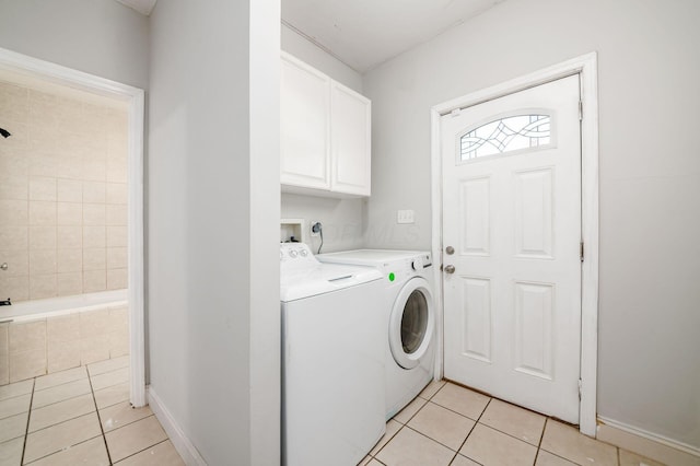 clothes washing area with light tile patterned flooring, cabinet space, independent washer and dryer, and baseboards