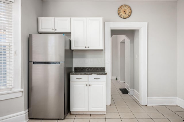 kitchen featuring white cabinetry, a wealth of natural light, light tile patterned floors, and freestanding refrigerator