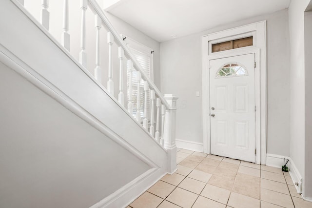 foyer featuring light tile patterned floors, stairway, and baseboards