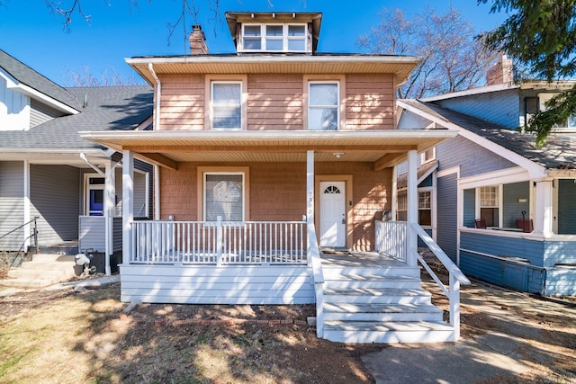 american foursquare style home with a porch and a chimney