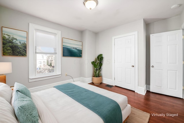 bedroom featuring dark wood finished floors, visible vents, and baseboards