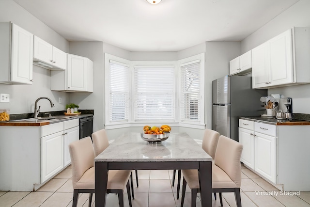 kitchen with light tile patterned floors, dishwasher, white cabinetry, and freestanding refrigerator