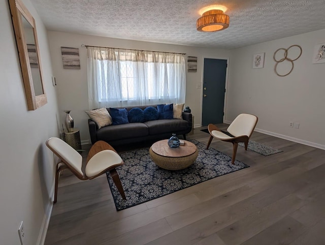 living area featuring baseboards, a textured ceiling, and wood finished floors