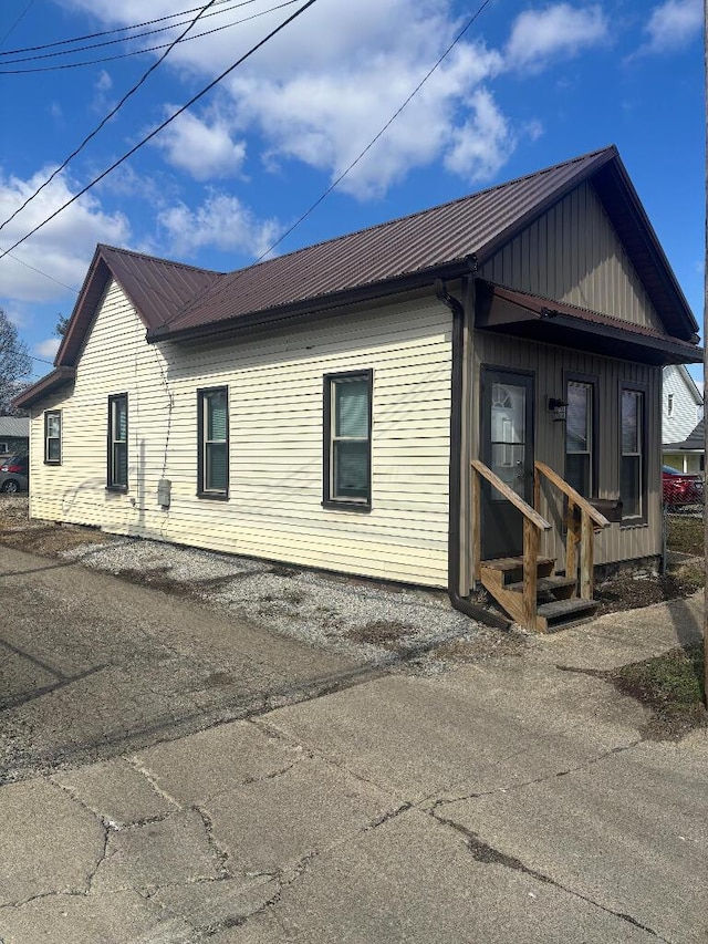 exterior space featuring entry steps, board and batten siding, and metal roof