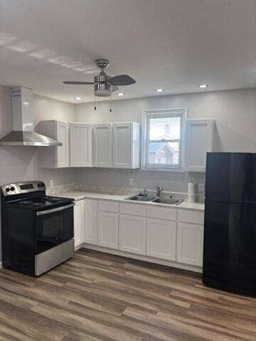 kitchen with stainless steel electric range oven, dark wood-style floors, freestanding refrigerator, a sink, and wall chimney range hood