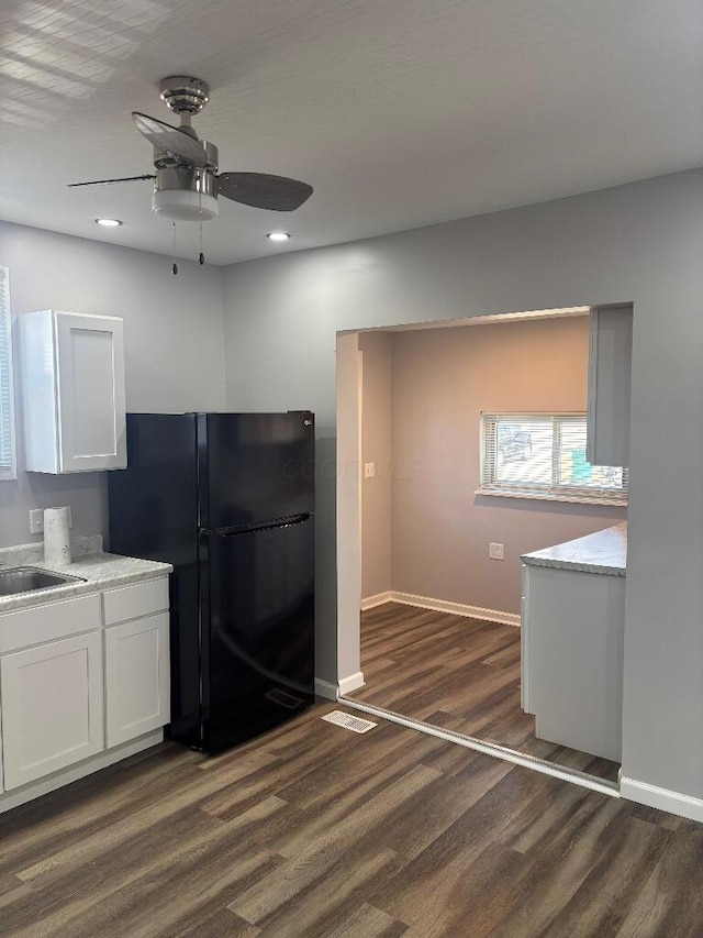 kitchen with baseboards, dark wood finished floors, freestanding refrigerator, white cabinets, and a sink