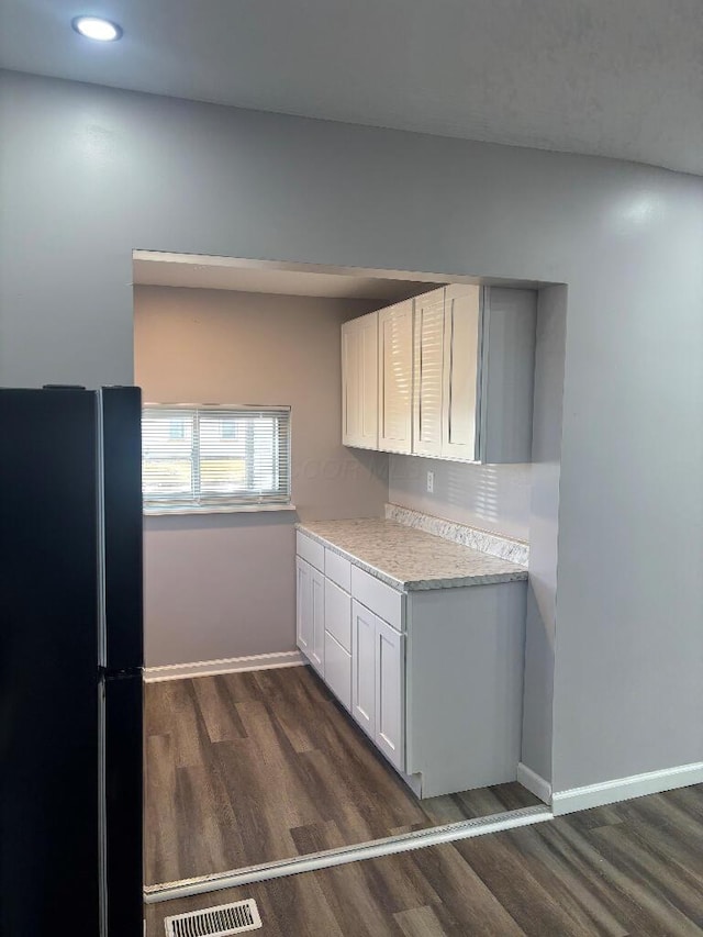 kitchen with visible vents, dark wood-style floors, freestanding refrigerator, light countertops, and baseboards