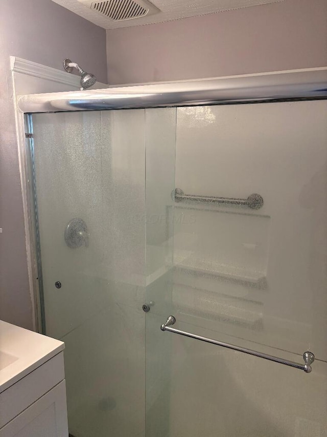 full bathroom with vanity, a shower stall, and visible vents