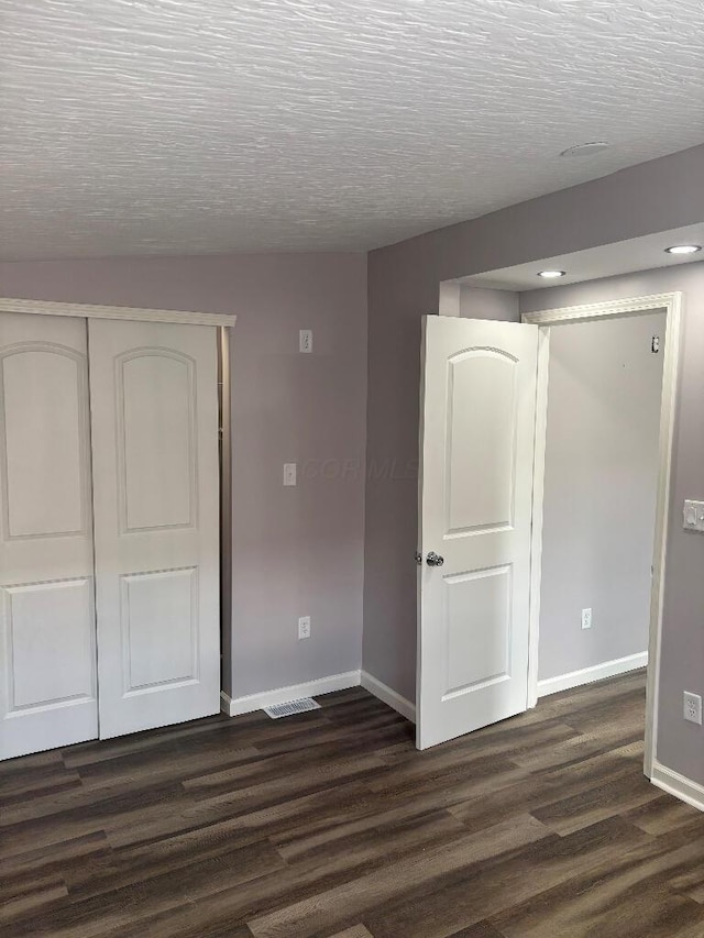 interior space featuring visible vents, a textured ceiling, baseboards, and dark wood-style flooring