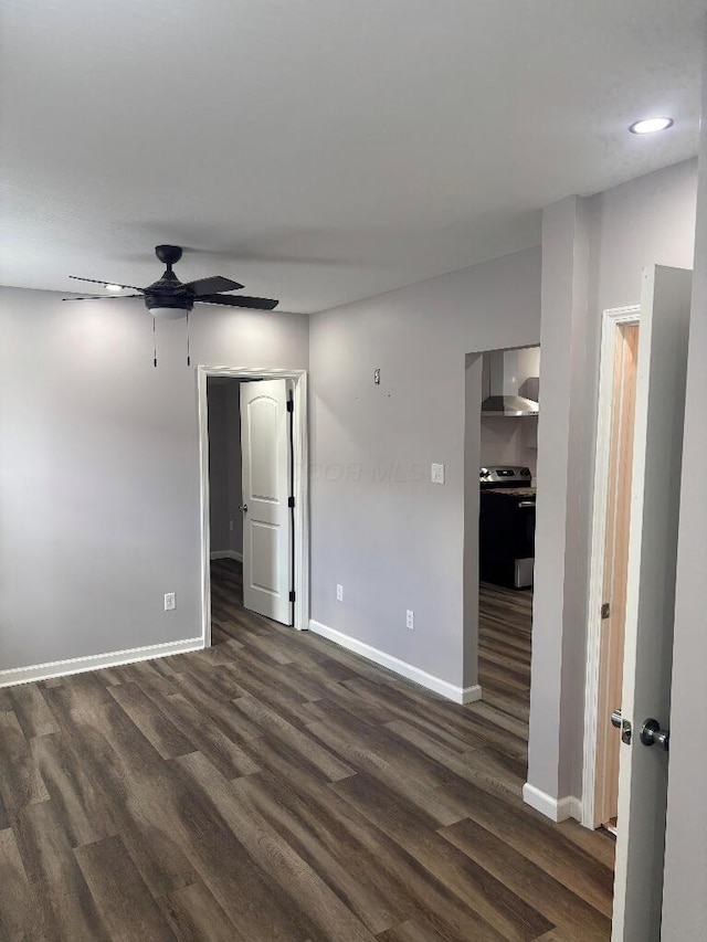 spare room with baseboards, dark wood finished floors, and a ceiling fan