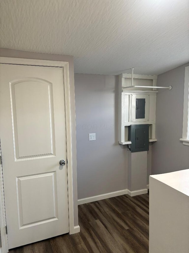 laundry room featuring electric panel, baseboards, a textured ceiling, and dark wood finished floors