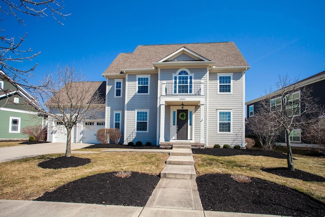 view of front of house featuring an attached garage, a front lawn, driveway, and a balcony