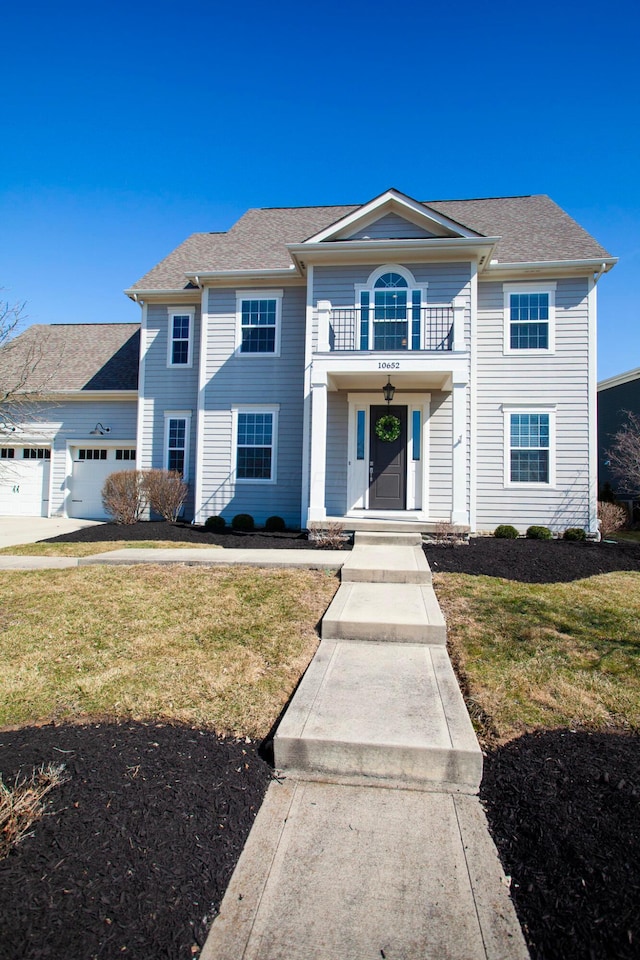 view of front of home featuring a front lawn, a balcony, an attached garage, and a shingled roof