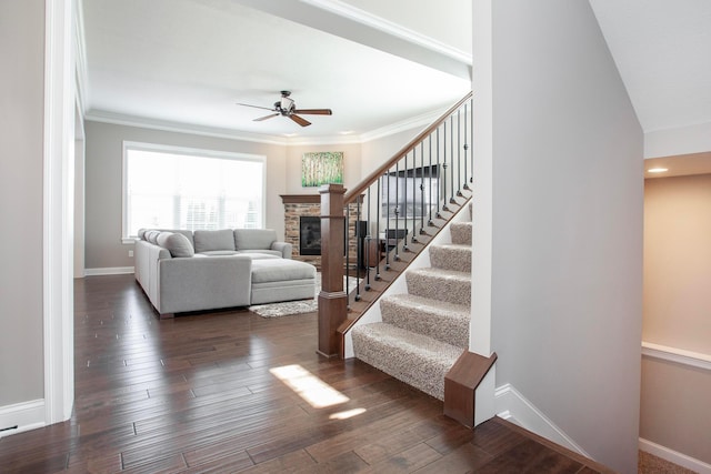 interior space with baseboards, a stone fireplace, wood finished floors, and ornamental molding