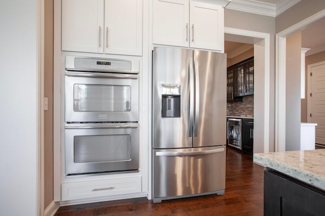 kitchen featuring light stone counters, stainless steel appliances, crown molding, decorative backsplash, and dark wood-style flooring