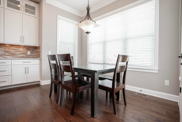 dining space featuring baseboards, dark wood-style floors, visible vents, and ornamental molding