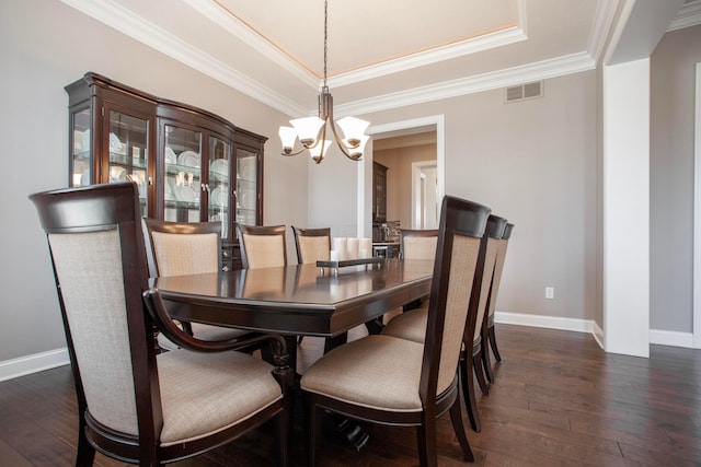 dining area featuring visible vents, baseboards, ornamental molding, dark wood-style floors, and a raised ceiling