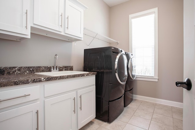 laundry room with baseboards, light tile patterned flooring, cabinet space, a sink, and independent washer and dryer