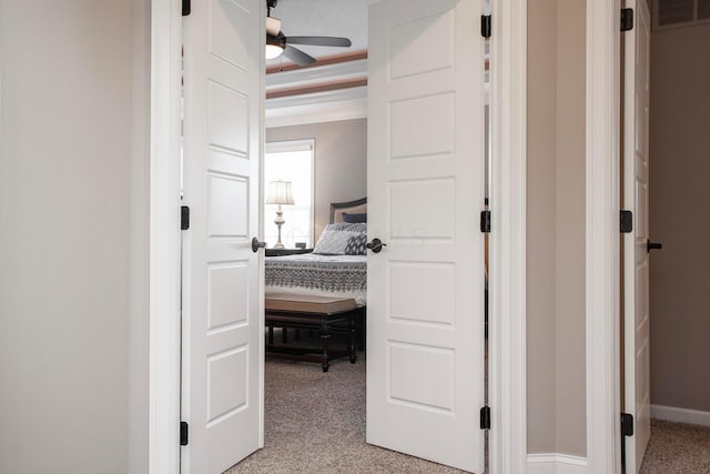 hallway featuring baseboards, light colored carpet, visible vents, and ornamental molding