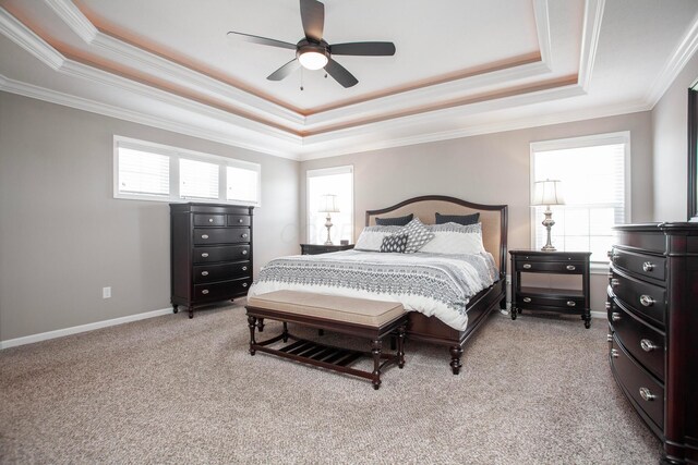 bedroom with baseboards, ceiling fan, crown molding, a raised ceiling, and light colored carpet