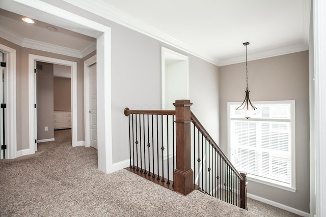 corridor with an upstairs landing, crown molding, baseboards, and carpet floors