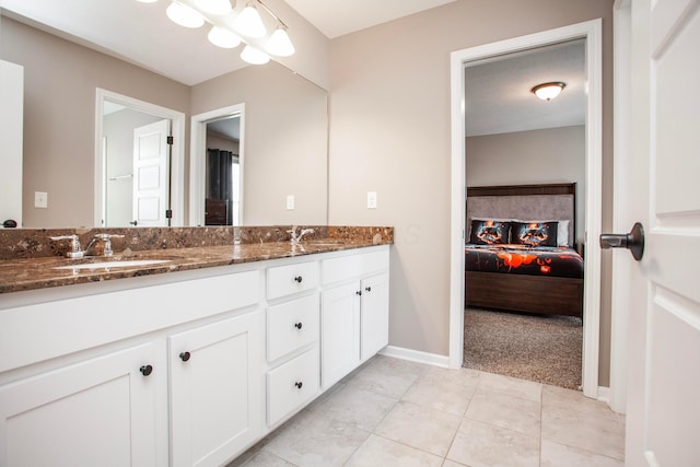 ensuite bathroom featuring baseboards, double vanity, tile patterned floors, ensuite bath, and a sink