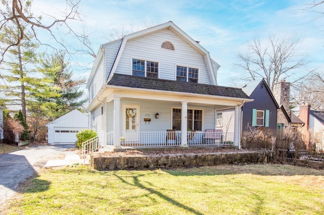 dutch colonial featuring a gambrel roof, a porch, a front yard, roof with shingles, and an outdoor structure