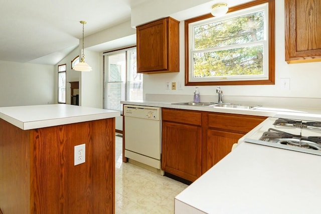 kitchen featuring white appliances, decorative light fixtures, light countertops, and a sink