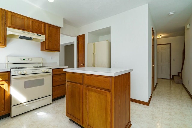 kitchen featuring white appliances, brown cabinetry, light floors, light countertops, and under cabinet range hood