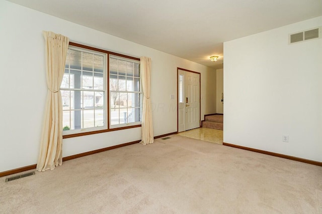 carpeted spare room featuring stairway, baseboards, and visible vents