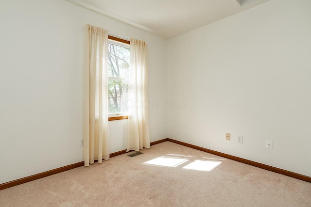 empty room with baseboards, visible vents, and light carpet