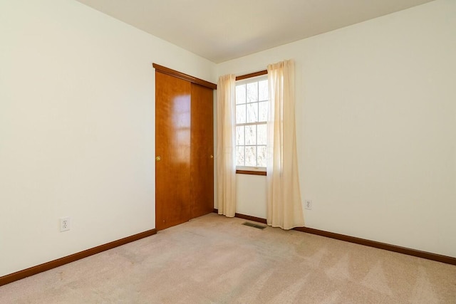 empty room with visible vents, baseboards, and light colored carpet