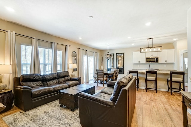 living room featuring light wood finished floors, a chandelier, recessed lighting, and baseboards