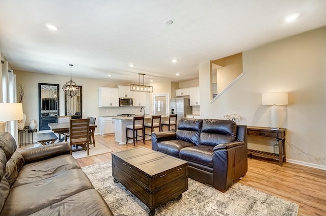 living area with an inviting chandelier, recessed lighting, baseboards, and light wood-type flooring