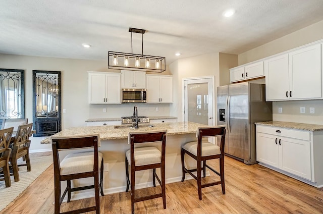 kitchen featuring white cabinetry, a kitchen breakfast bar, light wood-style floors, and stainless steel appliances