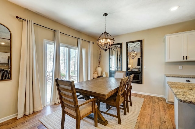 dining room with light wood-style flooring, a notable chandelier, and baseboards