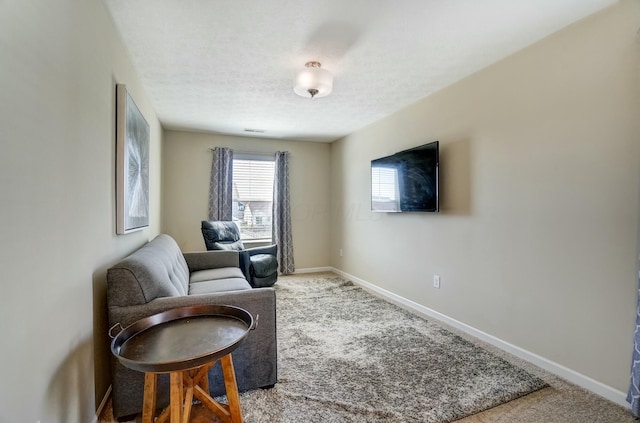 sitting room featuring carpet flooring, baseboards, and a textured ceiling