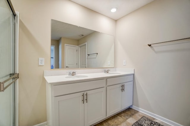 bathroom featuring double vanity, baseboards, and a sink