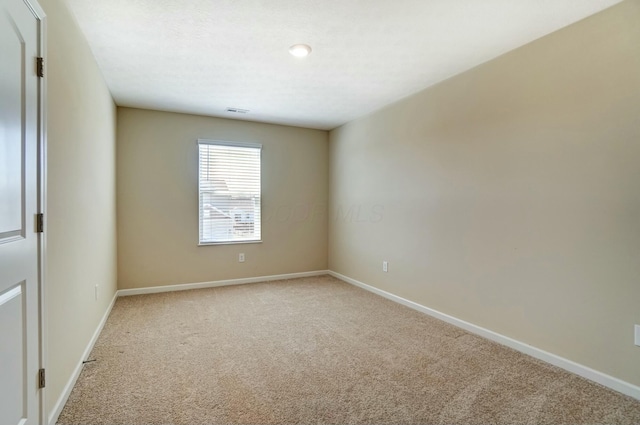 empty room featuring visible vents, baseboards, and light colored carpet