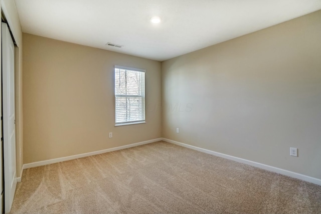 unfurnished room featuring visible vents, light colored carpet, and baseboards