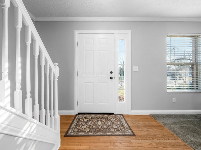 entryway featuring stairway, wood finished floors, baseboards, and ornamental molding