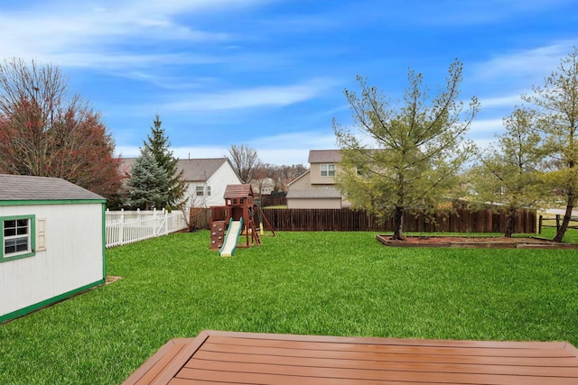 view of yard featuring an outbuilding, a playground, and a fenced backyard