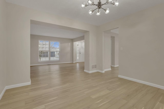 interior space featuring a notable chandelier, baseboards, light wood-style floors, and visible vents