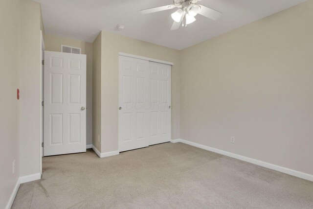 unfurnished bedroom with light carpet, visible vents, a closet, and baseboards