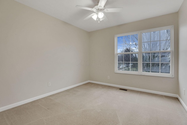 carpeted spare room with visible vents, a ceiling fan, and baseboards