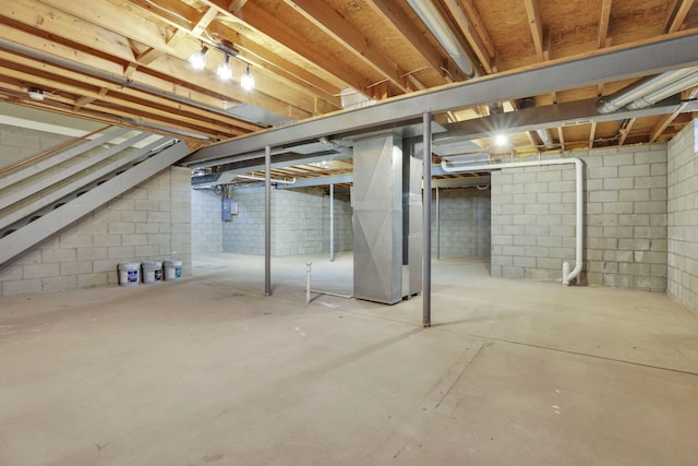 unfinished basement with heating unit and stairway